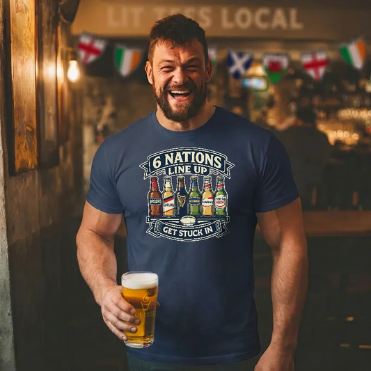 Man wearing a blue t-shirt with beer bottle graphics and 6 Nations Line Up text, holding a beer in a bar setting.