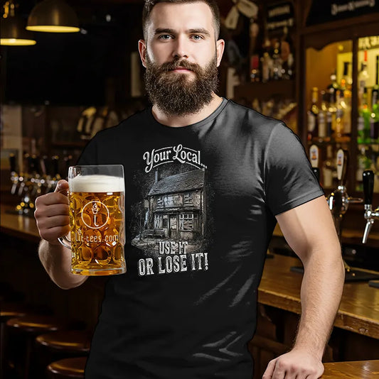 Man holding a beer mug wearing a black t-shirt with a graphic design and text saying'Your local use it or lose it' in a bar setting