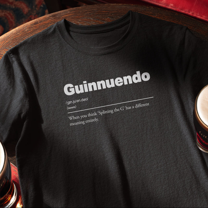 Black t-shirt with 'Guinnuendo' definition text on pub table with a mug and glass. Guinnuendo :: When you think 'Splitting the G' has a different meaning entirely.