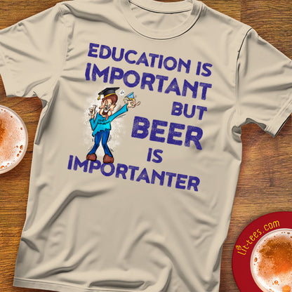 T-shirt with 'Education is important but beer is importanter' text and cartoon character on a wooden surface.