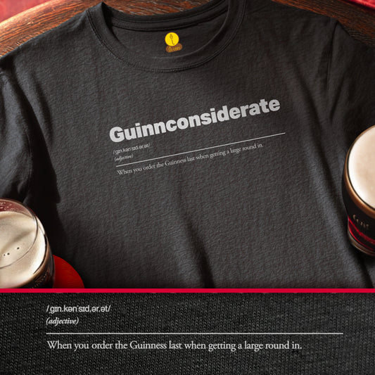 Black t-shirt with 'Guinnconsiderate' text design on a wooden surface with coffee cups.