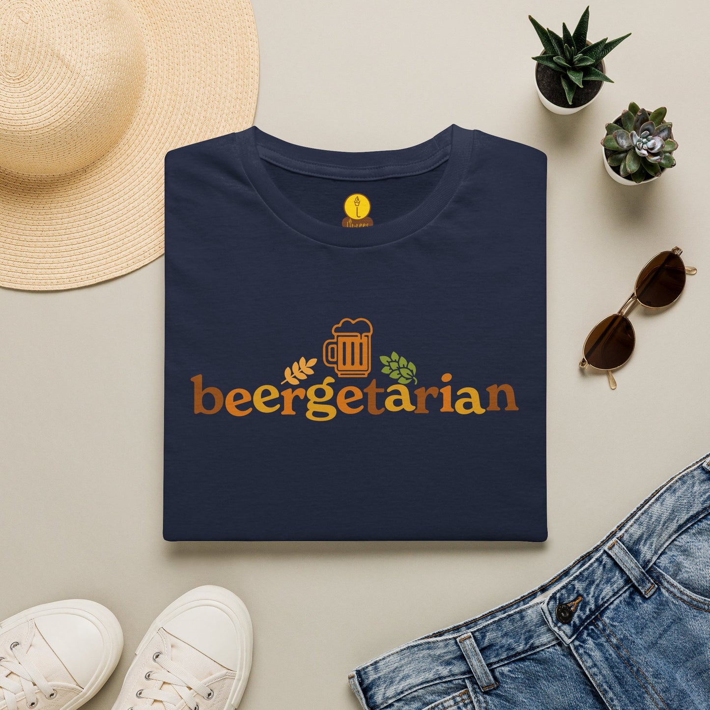 Navy t-shirt reading 'Beergetarian' by a hat, sunglasses, shoes, and plants on a light surface