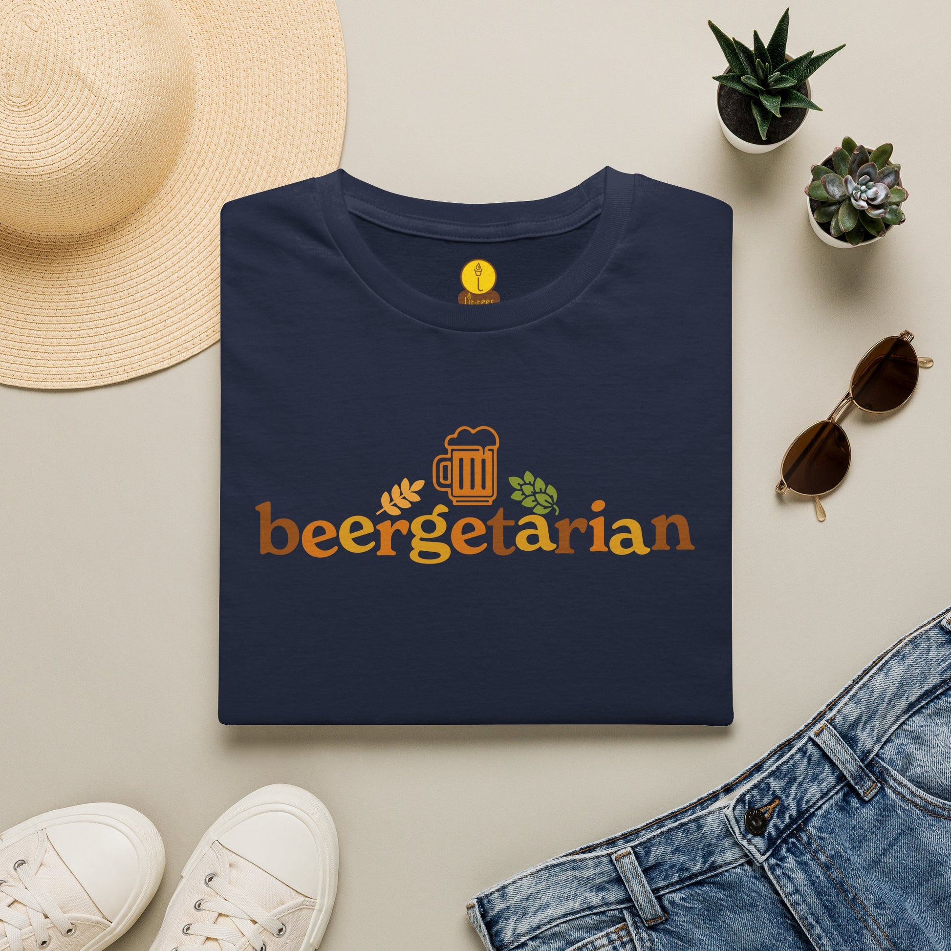 Navy t-shirt reading 'Beergetarian' by a hat, sunglasses, shoes, and plants on a light surface