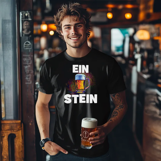Man standing in a pub setting holding a beer and wearing a funny T Shirt with the text Ein Stein