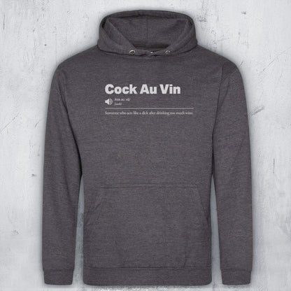 A dark heather gray pullover hoodie with a white graphic text print on the chest reading 'Cock Au Vin' and a small definition-style subtitle, shown against a light gray textured wall background.