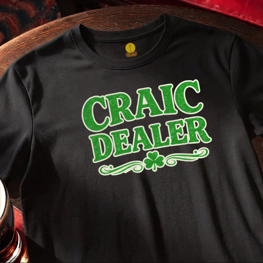 Black t-shirt with 'CRAIC DEALER' text in green on a wooden bar table