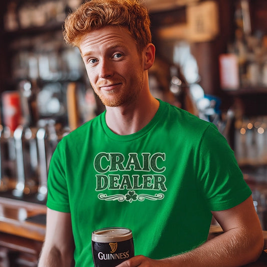 Man wearing a green 'Craic Dealer' t-shirt holding a pint of Guinness in a bar setting.