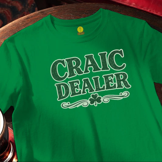 Green t-shirt with 'Craic Dealer' text and shamrock on a wooden bar table