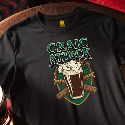 Black t-shirt with 'Craic Attack' design featuring a glass of beer and crossed sticks on a wooden bar table.