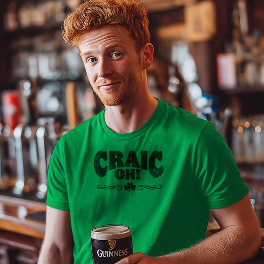 Man in a bar wearing a green 'Craic On!' t-shirt and holding a pint of Guinness 