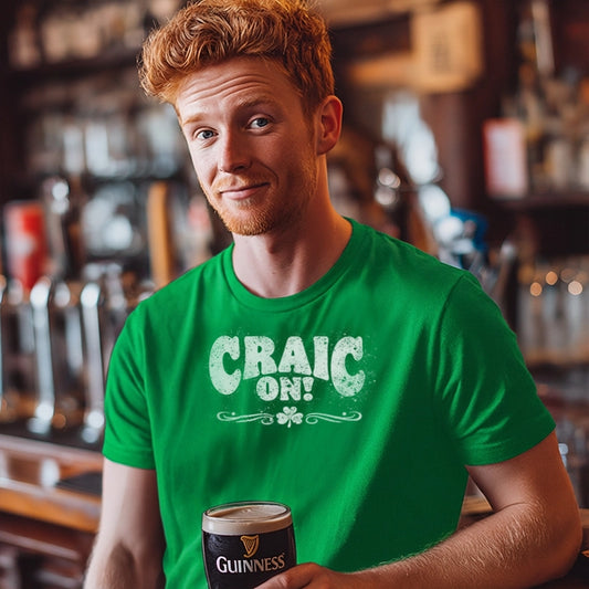 Man in a bar wearing a green 'Craic On!' t-shirt and holding a pint of Guinness 