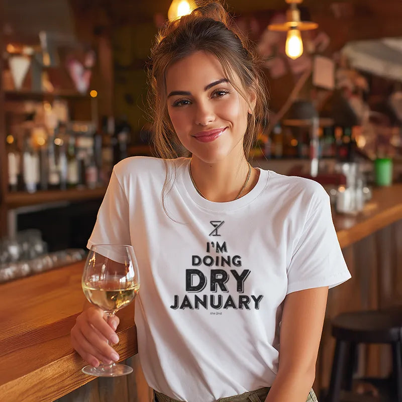 Woman in a bar wearing a 'I'm Doing Dry January' t-shirt holding a glass of wine.
