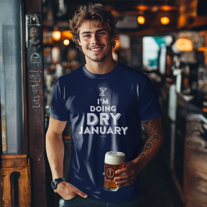 Man wearing a 'I'm Doing Dry January' t-shirt holding a beer in a bar.