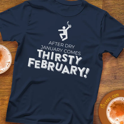 Navy blue t-shirt with 'After Dry January Comes Thirsty February!' text on a wooden surface with hot chocolate.