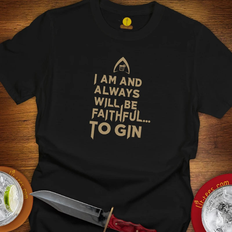 A black graphic t-shirt laid flat on a wooden surface, featuring a gold-colored text print that reads 'I AM AND ALWAYS WILL BE FAITHFUL TO GIN'.