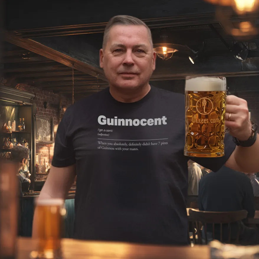 Man holding a large beer mug in a bar setting wearing a 'Guinnocent' t-shirt.