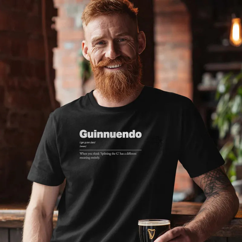 Man wearing a black t-shirt with 'Guinnuendo' text, holding a glass in a bar setting. Guinnuendo :: When you think 'Splitting the G' has a different meaning entirely.