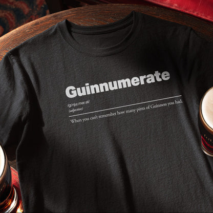 Black t-shirt with 'Guinnumerate' text design on a wooden surface with a can of Guinness. Guinnumerate :: When you can't remember how many pints of Guinness you had.