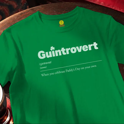Green t-shirt with 'Guintrovert' text on a wooden bar table with beer glass