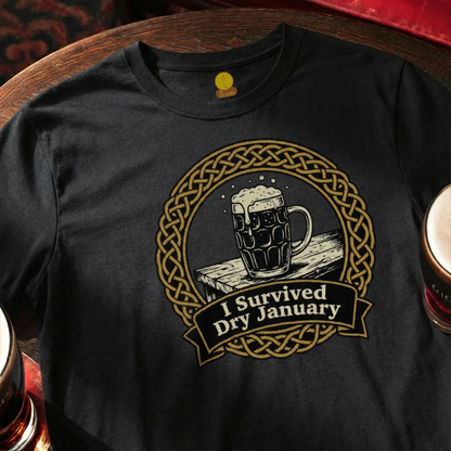 Black t-shirt with a graphic of a mug of beer and 'I Survived Dry January' text, placed on a wooden bar table.