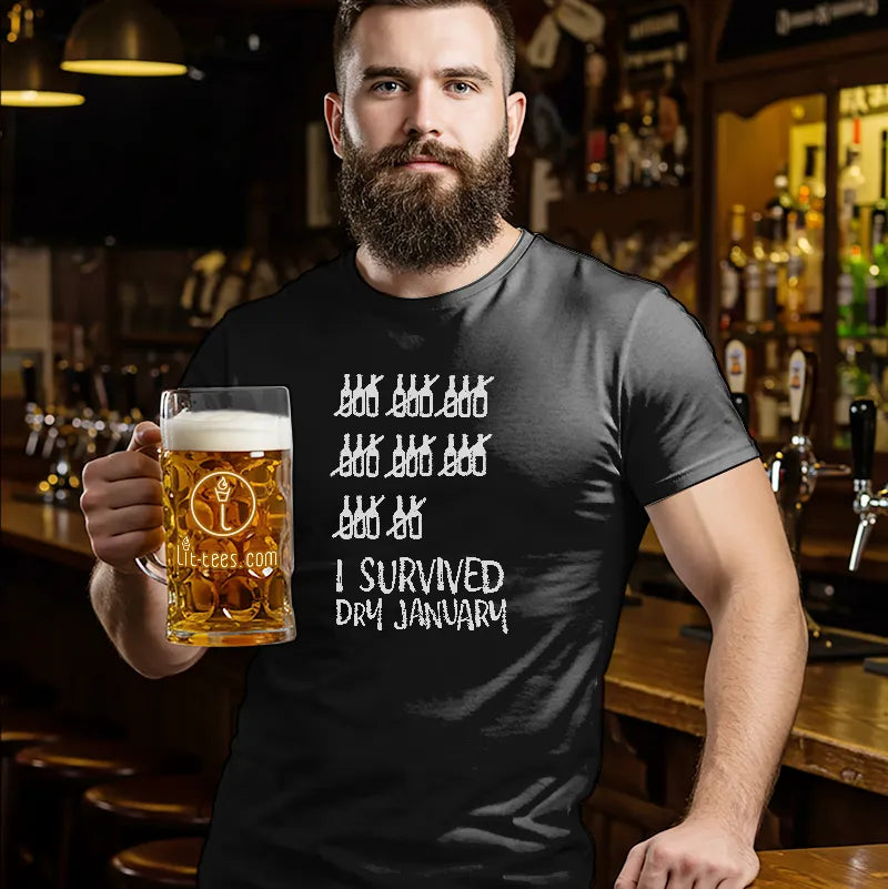 Man holding a pint of beer standing in a bar wearing a black t shirt with text saying 'I survived Dry January'