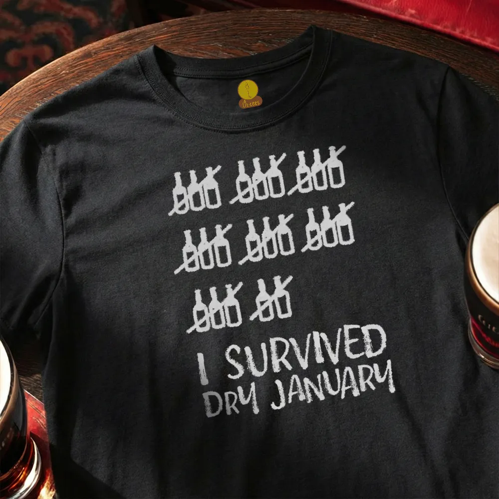Black t-shirt with white graphic and text 'I Survived Dry January' on a wooden bar surface