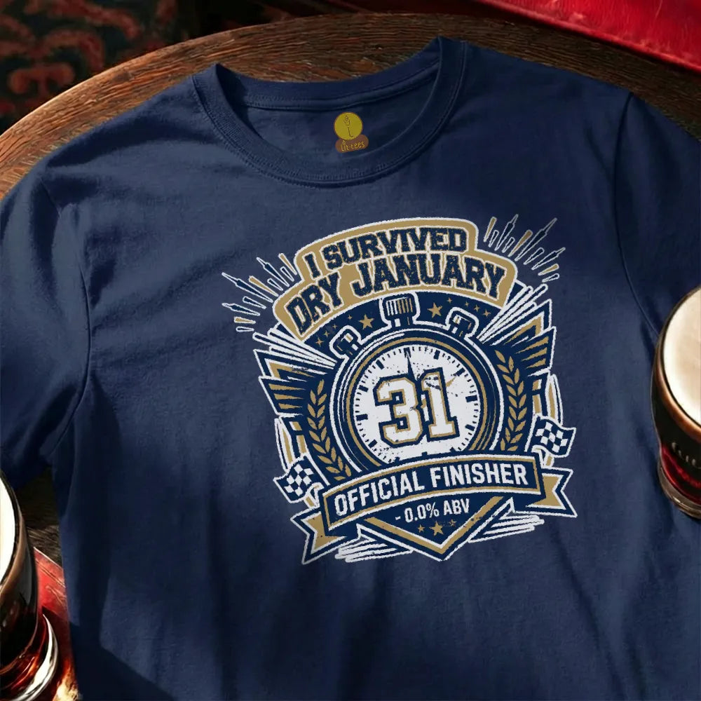 Navy blue t-shirt with 'I Survived Dry January' design on a wooden bar table with a glass of beer.