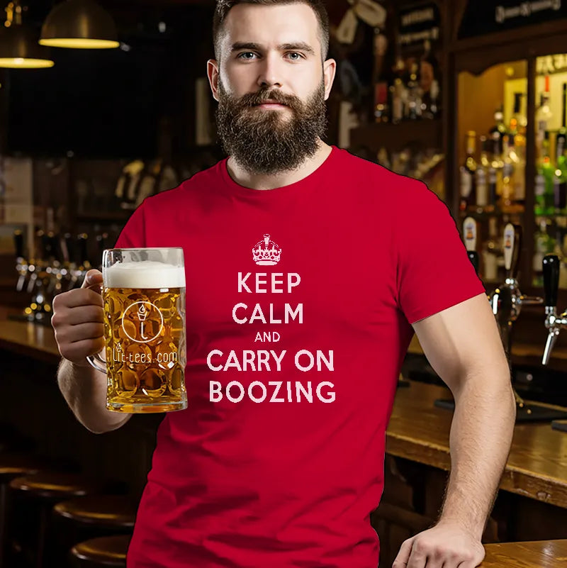 Man in bar holding a pint wearing a Red T Shirt with humourous text saying Keep Calm and Carry on Boozing