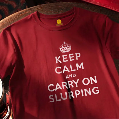Red T Shirt on round bar table with humourous text saying Keep Calm and Carry On Slurping