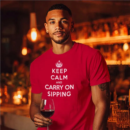 Man in bar holding wine glass wearing red t shirt with humourous text saying Keep Calm and Carry on Sipping