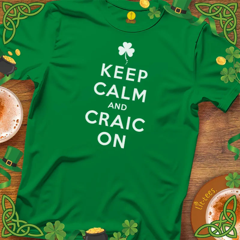 Green t-shirt with 'Keep Calm and Craic On' text on a wooden surface with St. Patrick's Day decorations.