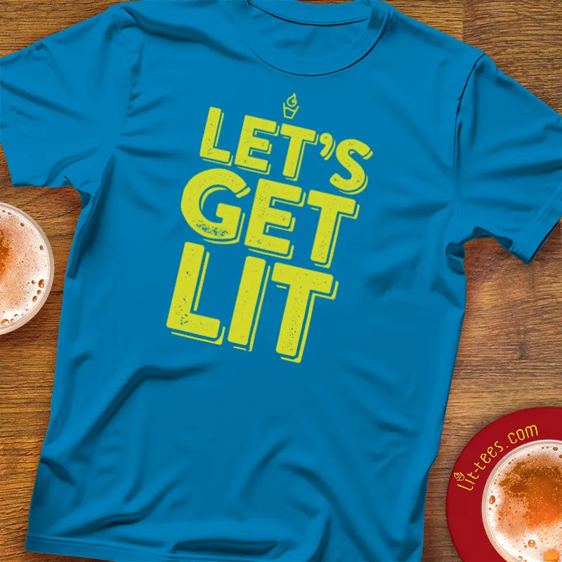 Blue t-shirt with 'LET'S GET LIT' text on a wooden pub table with drinks.