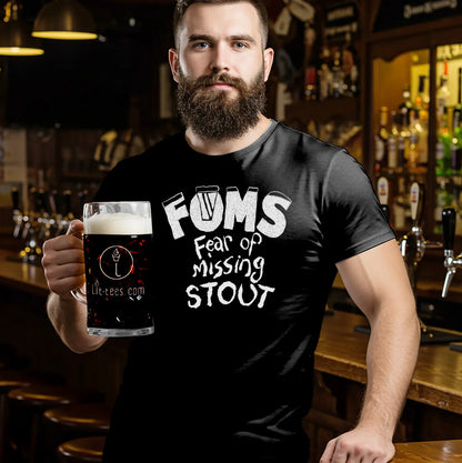 Man holding a Guinness wearing a black t-shirt with 'FOMS Fear of Missing Stout' text in a bar setting.