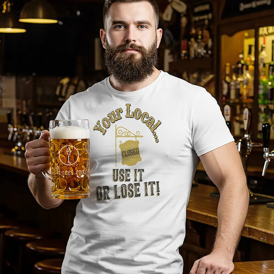 Man holding a beer mug wearing a white t-shirt with a humorous message saying 'Your local...use it or lose it' in a bar setting.