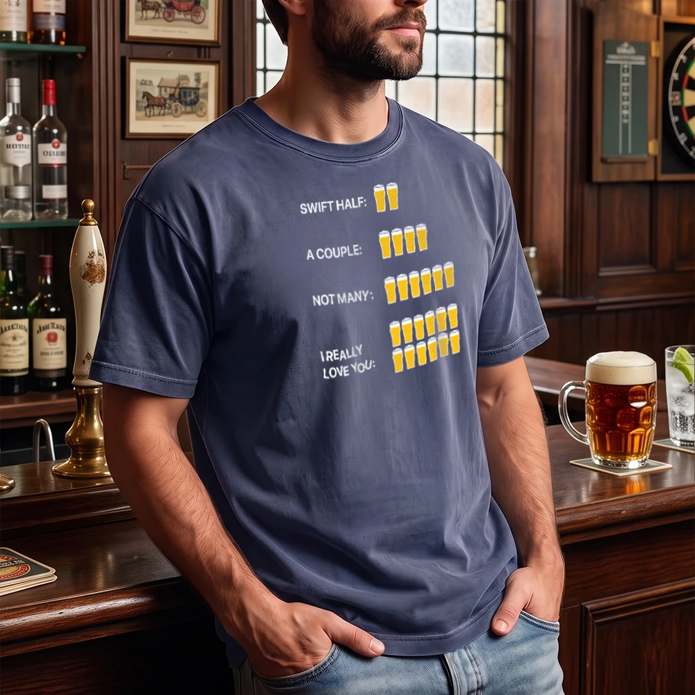 A man wearing a navy blue graphic t-shirt in a pub setting. The shirt features a humorous beer count graphic with text reading 'SWIFT HALF: A COUPLE: NOT MANY: I REALLY LOVE YOU:' next to corresponding numbers of beer glasses.