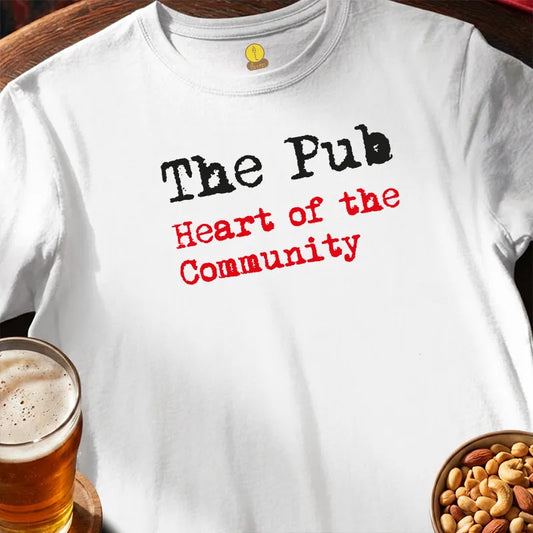 White t-shirt with 'The Pub Heart of the Community' text, glass of beer, and bowl of nuts on a wooden surface.