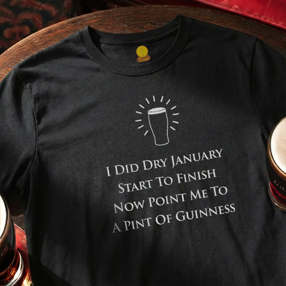 Black t-shirt with humorous Dry January text and graphic on a wooden bar table.