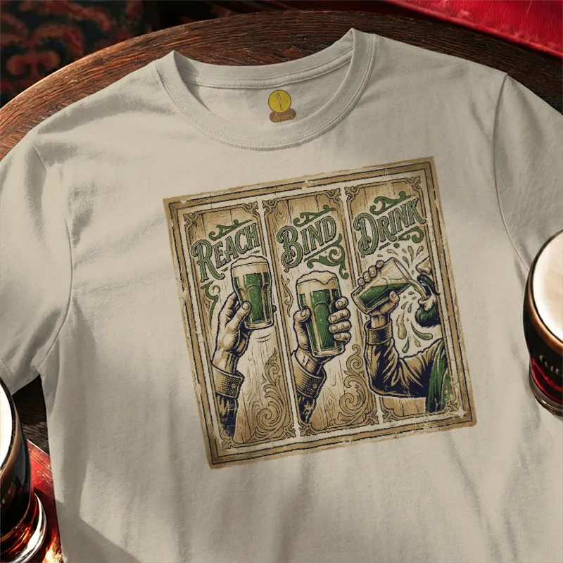 White t-shirt with graphic design of hands holding beer glasses and text 'Reach, Bind, Drink' on a wooden bar table