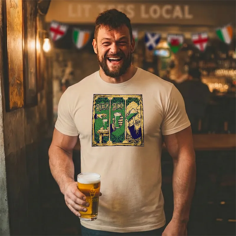 Man in a bar wearing a t-shirt with a graphic design and text saying 'Reach Bind Sip' holding a beer.