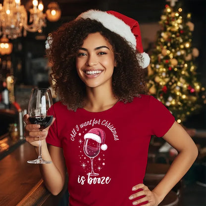Lady in a pub setting wearing a Christmas themed tee shirt reading 'All I want for Christmas is Booze' and holding a glass of wine. Glass has lit-tees.com printed on it.