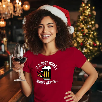 Woman in a red Christmas Tee Shirt reading 'Just what I always wanted' and Santa hat, holding a glass of wine in a festive setting.
