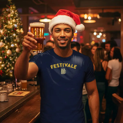 Man in a navy Christmas themed 'Festivale' t-shirt and Santa hat holding a beer in a festive bar setting. Glass has lit-tees.com printed on it.