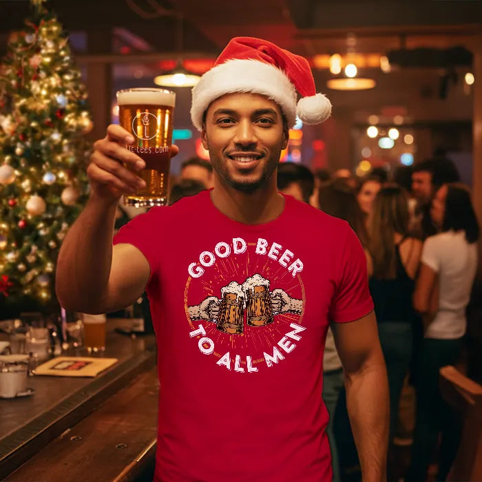 Man wearing a Santa hat and red 'Good Beer to All Men' shirt, holding a beer in a festive bar setting.
