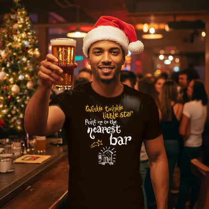 Man wearing a Santa hat and a t-shirt reading 'Twinkle twinkle little star, point me to the nearest bar', holding a beer in a bar setting.