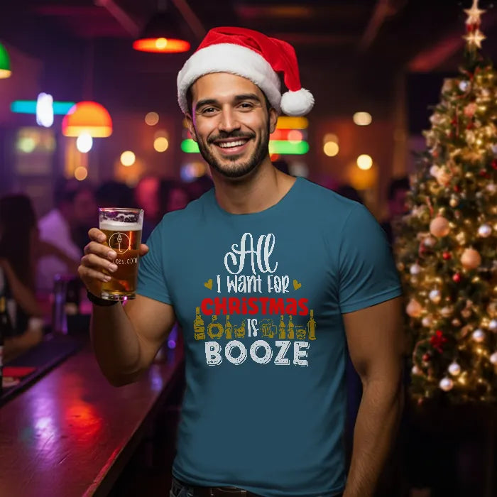 Man wearing a Santa hat and Christmas-themed shirt reading 'All I want for Christmas is Booze' holding a beer in a bar setting.