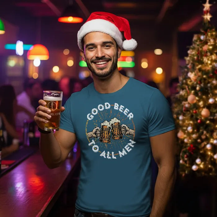 Man wearing a Santa hat and 'Good Beer to All Men' t-shirt holding a beer in a festive bar setting.