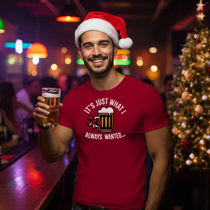Man wearing a Santa hat and red t-shirt reading 'Just what I always wanted', holding a beer in a bar setting with Christmas decorations.