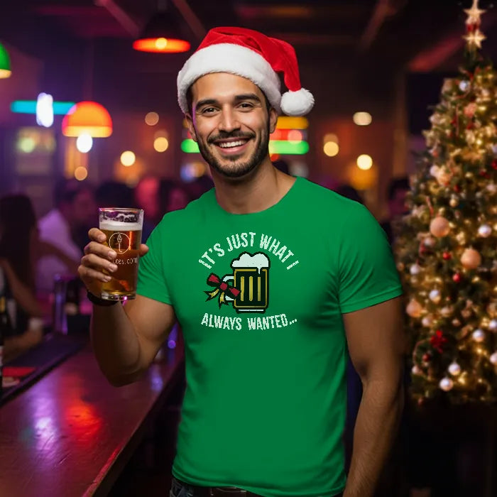 Man wearing a Santa hat and Christmas green t-shirt reading 'Just what I always wanted' holding a beer in a bar setting with Christmas decorations. Glass has lit-tees.com printed on it.