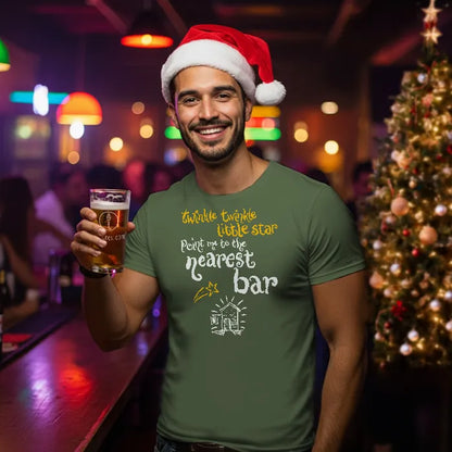 Man wearing a Santa hat and green t-shirt with a Christmas-themed quote, reading 'Twinkle twinkle little star, point me to the nearest bar', holding a beer in a bar setting.