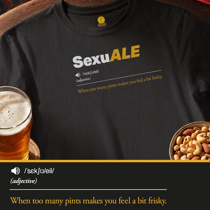 A black graphic T-shirt laid flat with a beer glass on the left and a bowl of nuts on the right. The shirt has a printed dictionary-style definition reading 'SexuALE' with the phrase 'When too many pints makes you feel a bit frisky.